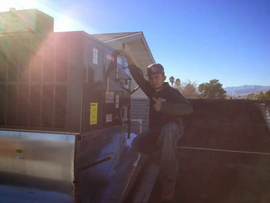 HVAC technician performing AC Tune-Up on a rooftop unit in Adrian